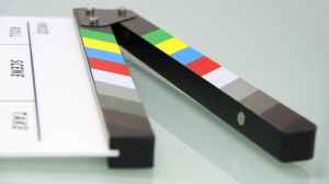 "Film Friday" - image shows an opened clapperboard with raindow colored stripes on the top, lying on a table.