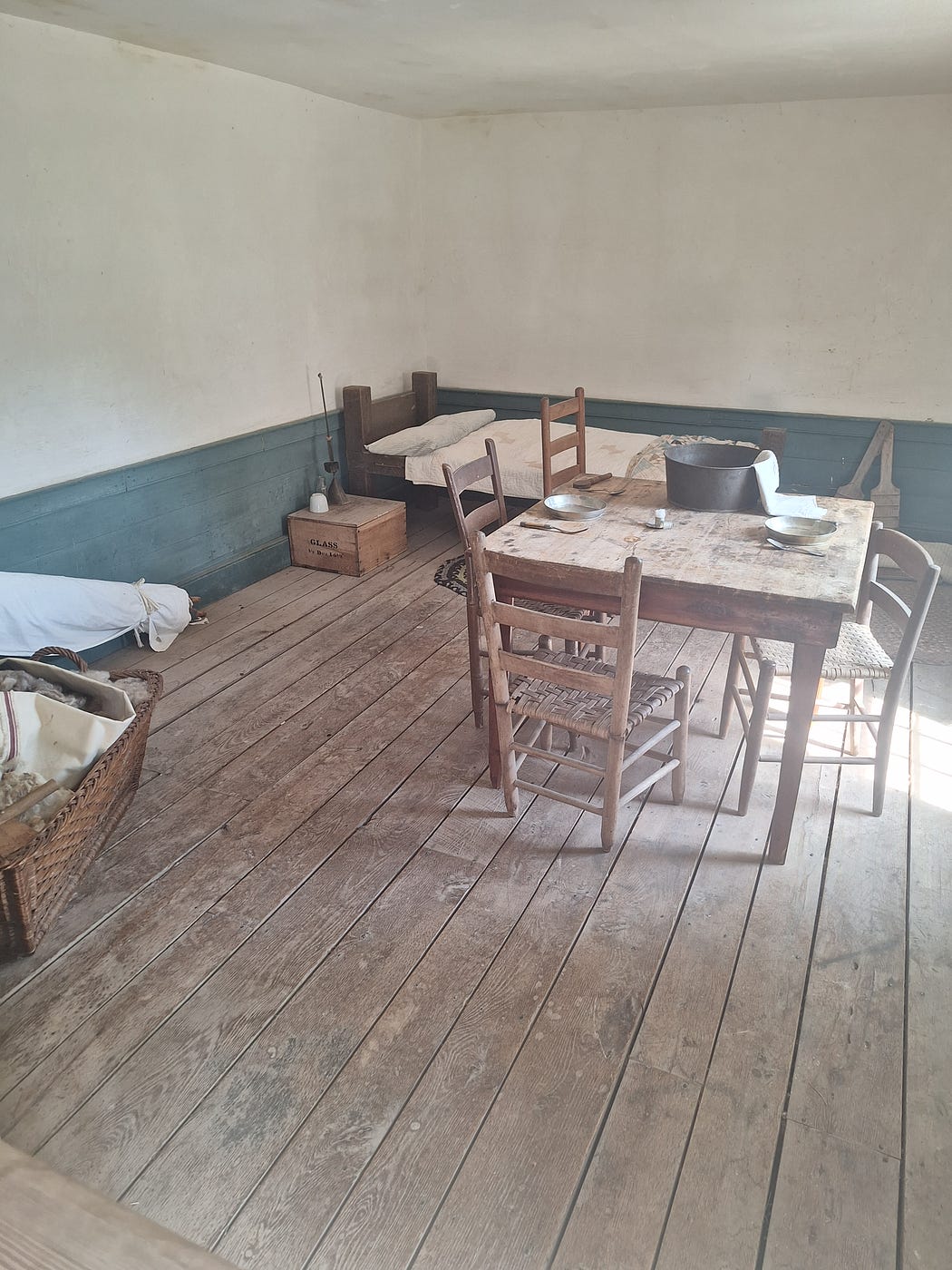 A simple room with wood floor, a bed, wood table and chairs